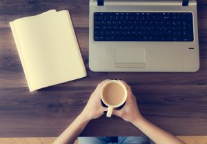 Office desk with person holding a cup while working. View from above.