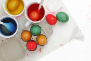 Colored Easter eggs and liquid color dyes on white background